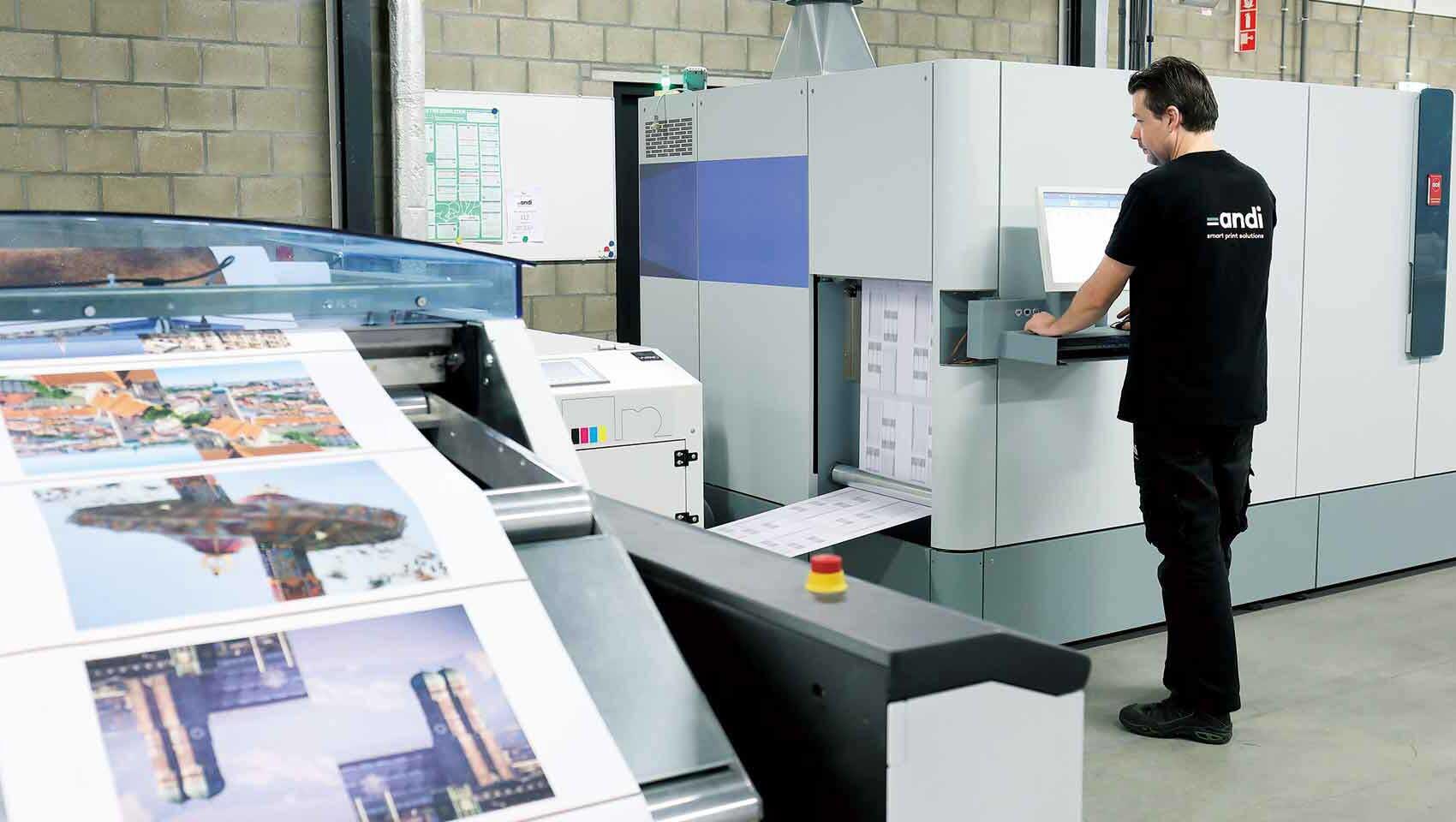 A flexographic printing press with large rollers, printing a simple logo onto cardboard.