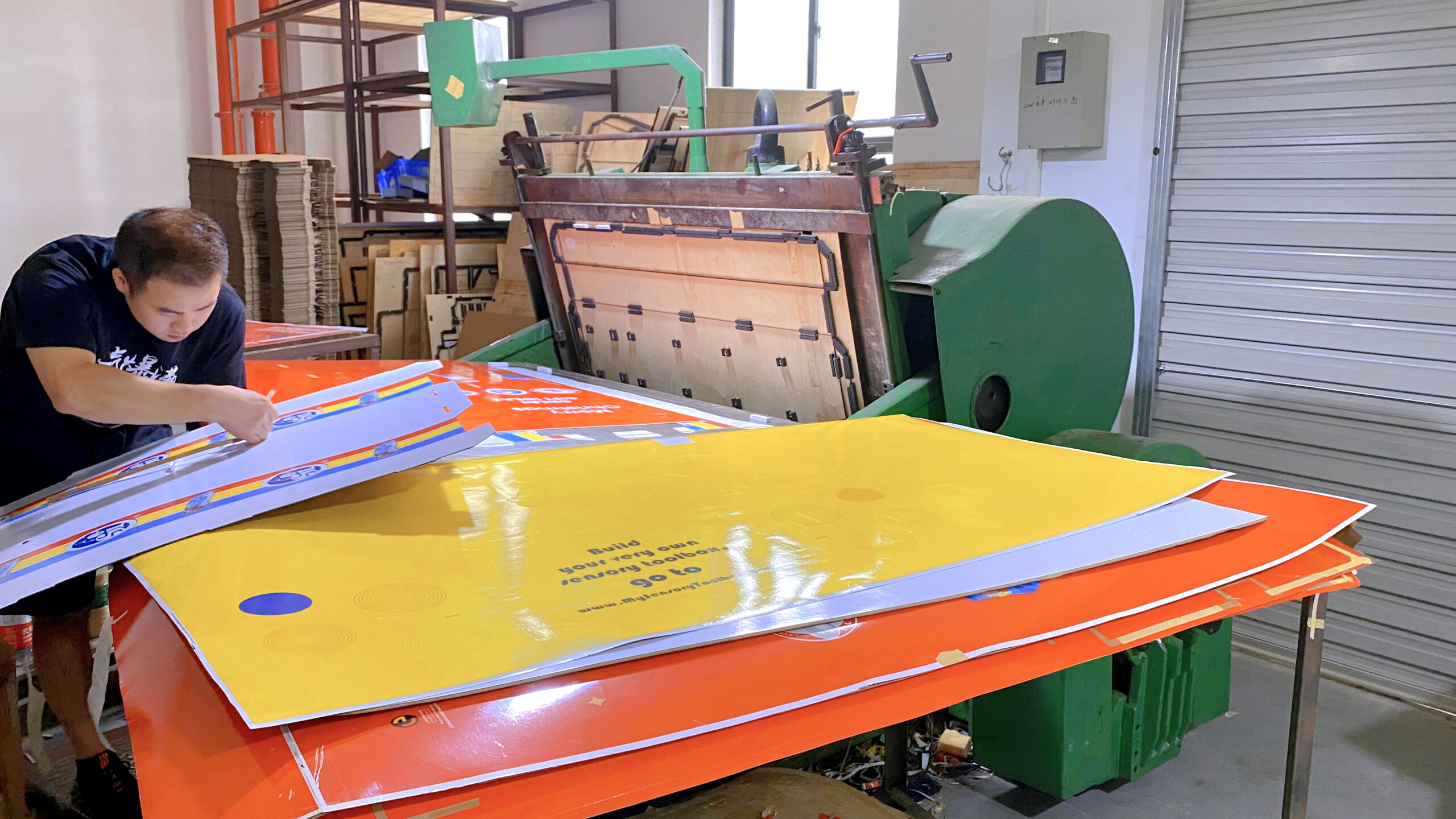 DIY Cardboard Display Stand Step-by-Step A person cutting cardboard according to a template to make a display stand