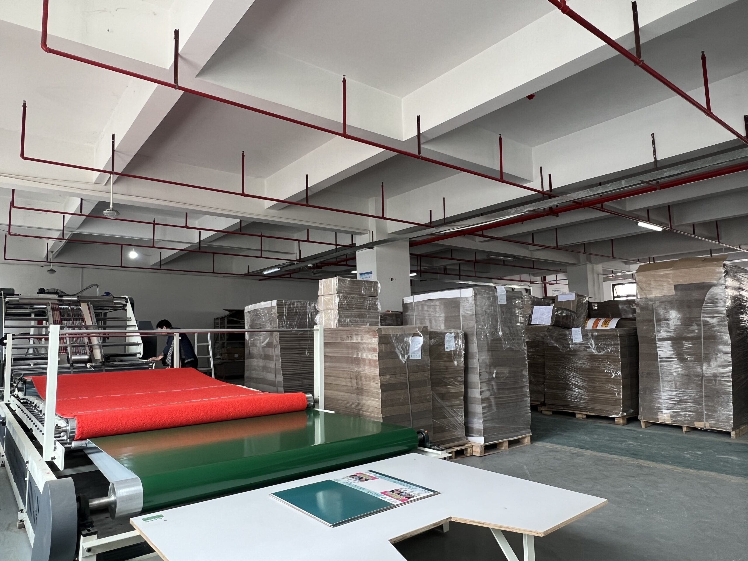An automated die-cutting machine processing cardboard sheets in a factory.