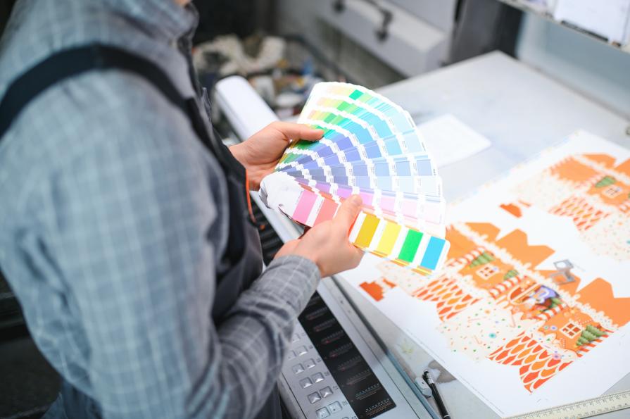 A close-up of a Pantone color swatch next to a printed cardboard display showing a perfect match